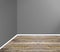 Empty room corner with wooden floor and grey wall