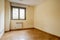 An empty room with cream painted walls, dark oak parquet, aluminum radiator and brown anodized aluminum windows