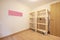 An empty room with empty cargo shelves made of unvarnished wood and laminated flooring