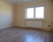 Empty room with laminate floor, radiator and plastic window