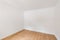 Empty room with laminate flooring and newly painted white wall in refurbished apartment. Repair and construction concept