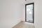 Empty room with laminate flooring and newly painted white walls with door to a balcony. Typical building in Spain with