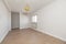 Empty room with light wood flooring, freshly painted plain white walls