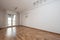 Empty room of a loft apartment with white painted walls, plaster moldings on the ceiling and exit to a terrace with aluminum and