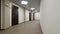 Empty, round corridor with light beige walls and closed, dark brown doors. Closed doors along a lighted corridor in the
