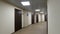 Empty, round corridor with light beige walls and closed, dark brown doors. Closed doors along a lighted corridor in the