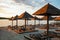 Empty rows resting places on evening sandy beach with brown wooden loungers and umbrellas