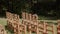 Empty rows of wooden chairs stand in the sun on green lawn in the park.