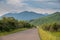 Empty rural road in mountains with morning blue cloudy sky