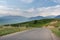 Empty rural road in mountains with morning blue cloudy sky