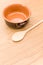 empty rustic terracotta kitchen bowl and spoon on a wooden tabletop