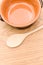 empty rustic terracotta kitchen bowl and spoon on a wooden tabletop