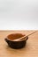 empty rustic terracotta kitchen bowl and spoon on a wooden tabletop