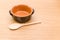 empty rustic terracotta kitchen bowl and spoon on a wooden tabletop with text space