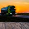 Empty rustic wood table top with motion blurred truck at sunset