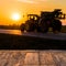 Empty rustic wood table top with tractor silhuette at sunset background. Can montage or display your products