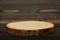 Empty rustic wooden slice serving board on dark brown wooden table.