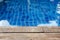 Empty rustic wooden table in front of blurred background of swimming pool.