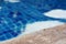 Empty rustic wooden table in front of blurred background of swimming pool.