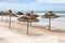 Empty sandy beach at stormy weather, sun umbrellas from palm leaf are on sand