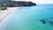 Empty sandy beach with two parasols and greenery by the turquoise clear sea. Aerial view