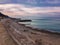 Empty sea shore with breakwaters against a cloudy sky.