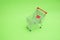 Empty shooping trolley cart on green background