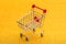Empty shopping trolley on a golden radiant background. Shop basket for products.