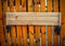 Empty signboard made of planks hanging on a wooden fence.