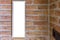 Empty small long rectangular picture frame hanging on a brick wall close to a corner