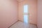 Empty small room with whitewashed floating laminate flooring and newly painted pink wall in background