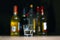 Empty small shots glass in front of multiple blurry different strong spirits alcohol bottles in darkbackground