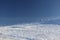 Empty snow-covered slope in the mountains for free skiing against the blue sky. Frosty winter