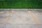 Empty space concrete parking lot and yellow line with green bush in the background.