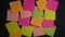 Empty square multi-colored stickers hang on a black board, business concept