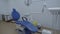 Empty Stomatology room equipped with blue dental unit, furniture, operating lamp