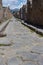 Empty stone street with ruins in Pompeii, Italy. Antique road in italian ancient town against mountain. Abandoned street.