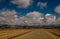 Empty straight road on a desert and blue scattered clouds sky
