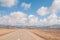 Empty straight road on a desert and blue scattered clouds sky