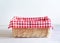 Empty straw basket with checked red picnic cloth.