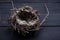 Empty straw nest with twigs on a wooden background.