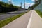 An empty street, pavement and bicycle path separated by noise barriers