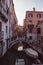 Empty streets and bridges of Venice, A small bridge and pink orange houses reflecting over a canal and a traditional gondola