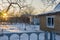 Empty suburban plot covered with snow and left for the winter brick cottage house in wintery evening at sunset. Russian dacha