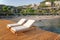 Empty sun beds deck chairs with mattresses on a wooden pier overlooking the blue Mediterranean Sea