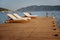 Empty sun beds deck chairs with mattresses on a wooden pier overlooking the blue Mediterranean Sea