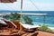 Empty sun loungers under an umbrella on the patio against the backdrop of the sea