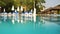 Empty sunbeds and closed parasols on morning, by the hotel pool. Photographed from water level. Vacation background, space for