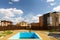 Empty Swimming Pool in the future garden. Modern cottages, blue sky white clouds. Residential compound.