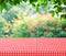 Empty table and red tablecloth with blur green leaves bokeh back